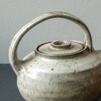 Set of ceramic teapot and four cups on a dark surface with a gray background