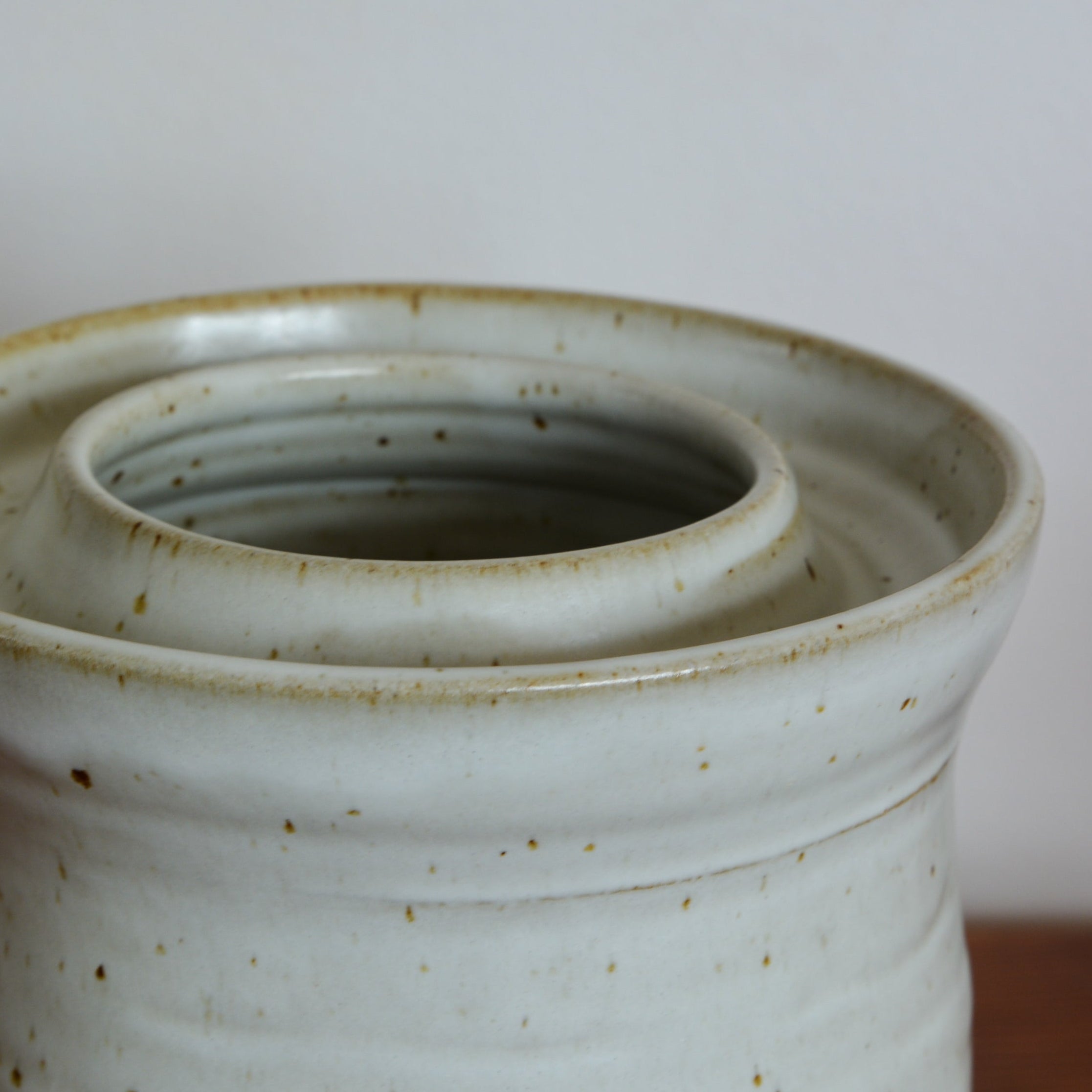Stack of ceramic pots with a speckled glaze on a neutral background